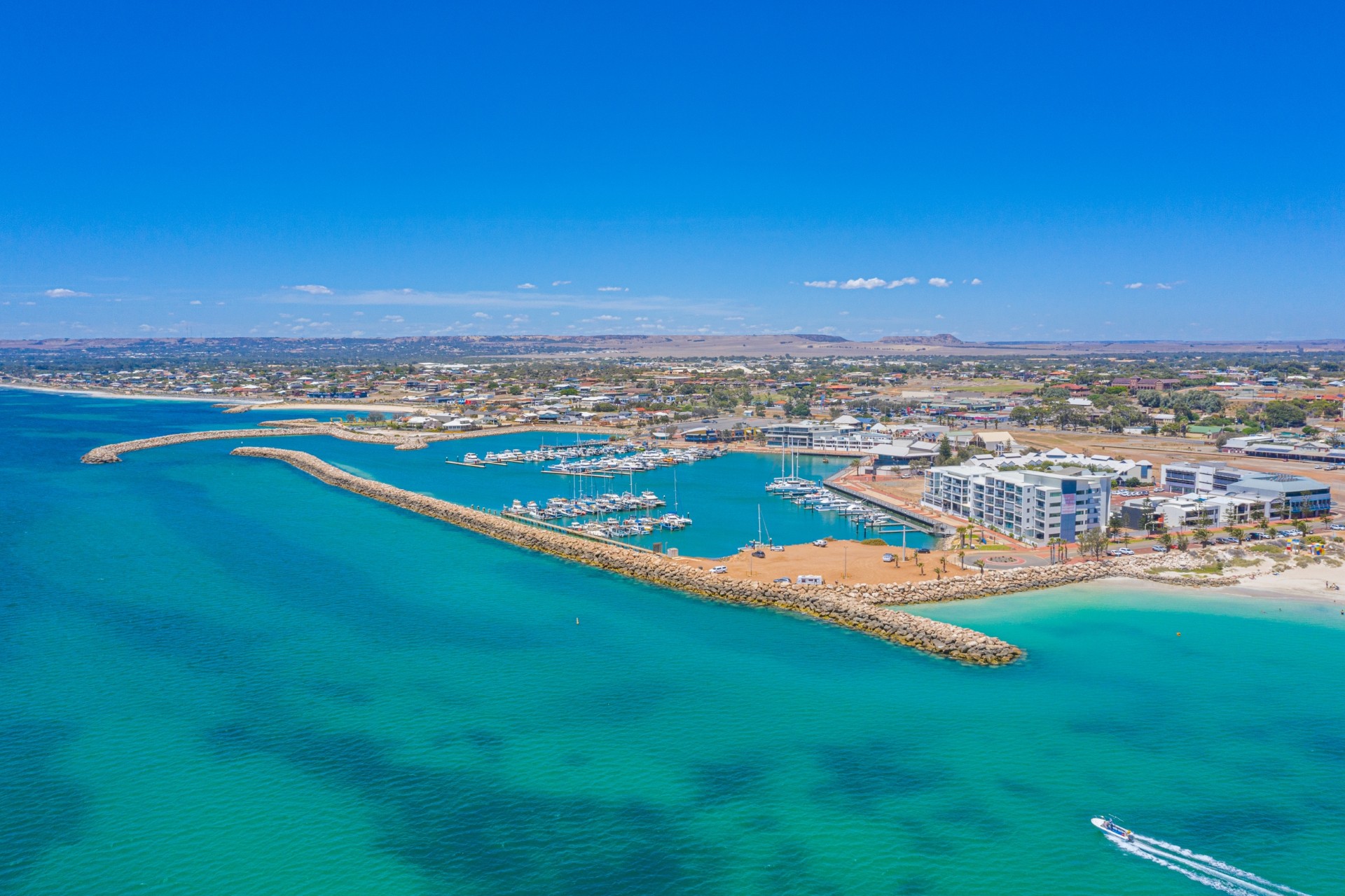 Aerial view of the Geraldton marina and coastline, with boats moored inside the breakwater and the town stretching inland